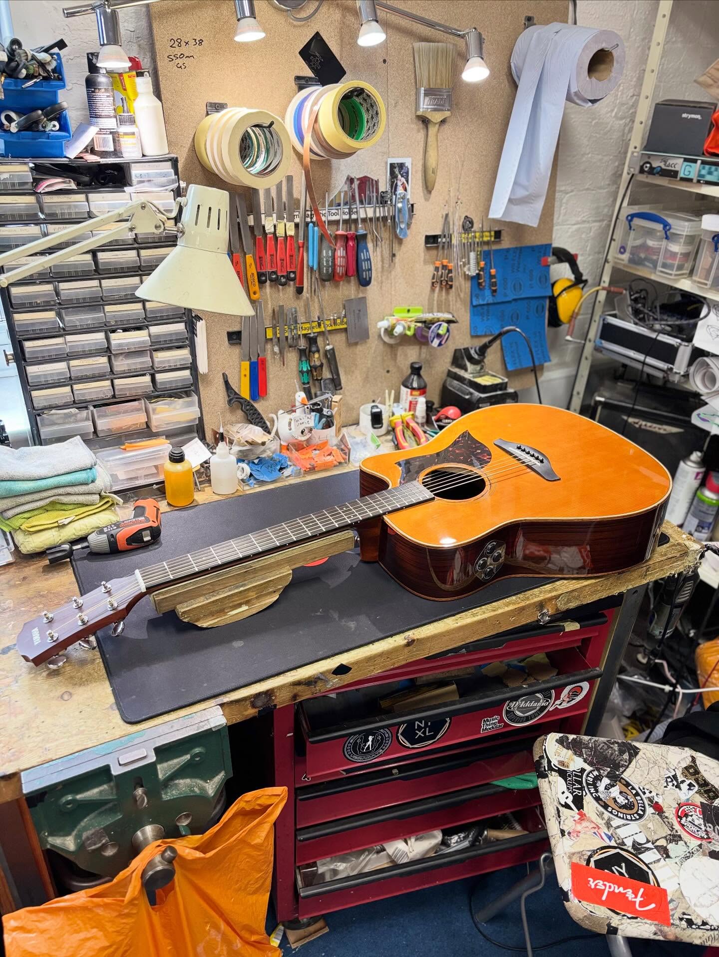 Acoustic guitar on a busy repair workbench